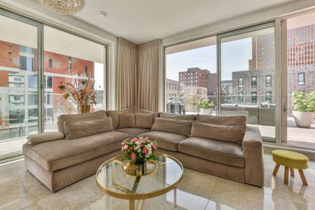 White cabinets with wooden counter of modern kitchen and dining table set in living room of apartmentの写真素材