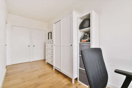 Comfortable armchair next to a table with computer monitors by the window in a bright spacious home...