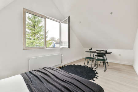 Home interior design of bedroom with bed and wooden wardrobe placed in corner near window in modern apartmentの写真素材