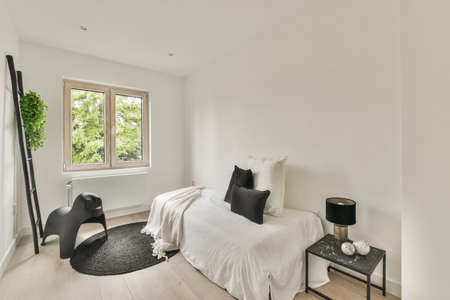 Home interior design of bedroom with bed and wooden wardrobe placed in corner near window in modern...