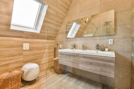 Flush toilet located between sink and shower in small tiled bathroom of contemporary apartmentの写真素材