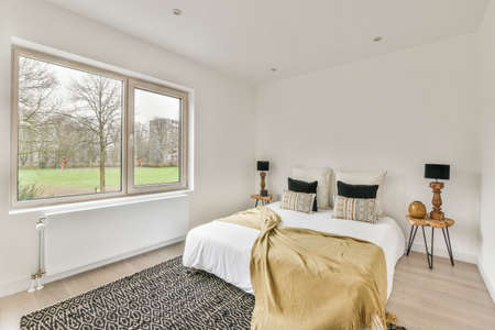 Home interior design of bedroom with bed and wooden wardrobe placed in corner near window in modern apartmentの写真素材