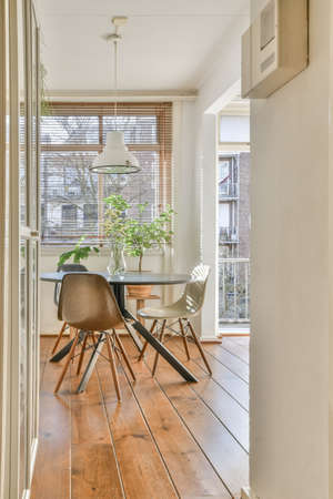 Spacious minimalist style dining room with table and chairs in modern apartment with white walls and...