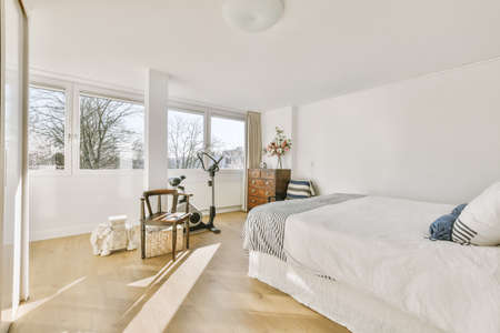 Home interior design of bedroom with bed and wooden wardrobe placed in corner near window in modern...