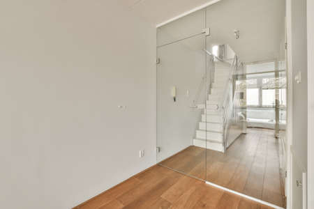 White hallway with wooden stairway leading to second floor of modern luxury apartment with minimalist interior designの写真素材