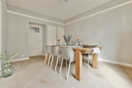 Interior of spacious light dining room with fireplace and elegant chandelier located near kitchen with modern furniture and appliancesの写真素材