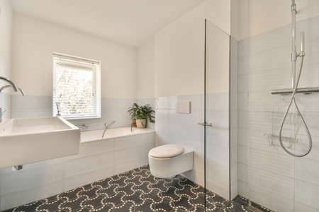 Sink base cabinet and mirror cabinet in white tiled bathroom with wall hung toilet