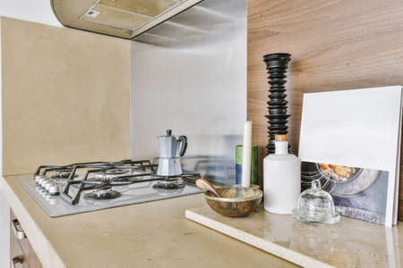 Fragment of interior of light narrow home kitchen with minimalist style brown furniture with sink...