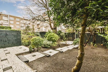 Neat paved patio with small garden near wooden fence