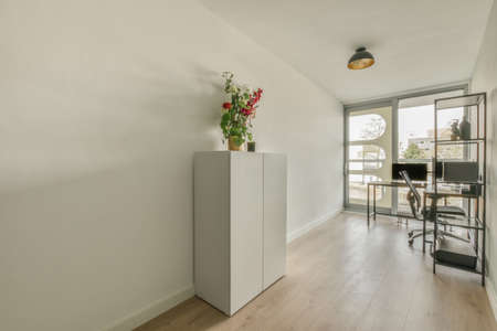 Comfortable chair placed near desk with computer monitors and whiteboard in light workplace in modern apartmentの写真素材