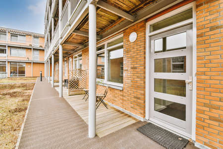 The front view of a brick building with signs, pavement and wooden doors lead to the apartmentの写真素材