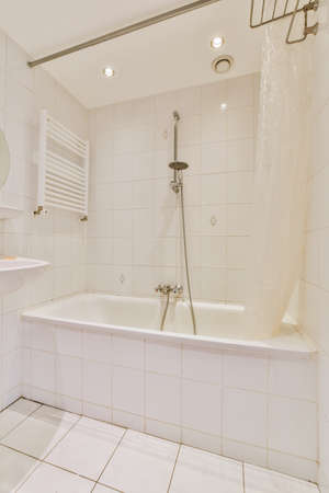 Sinks with mirrors and clean bathtub in modern bathroom with white tiled walls