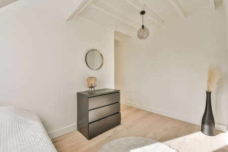 Comfortable bed placed near green wall in modern minimalist style mansard bedroom with windows