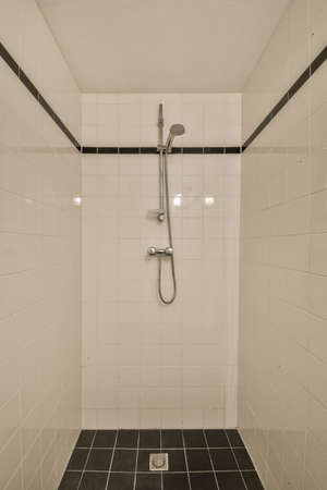 Flush toilet located between sink and shower in small tiled bathroom of contemporary apartmentの写真素材
