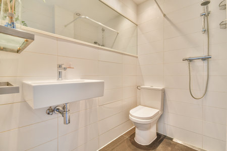 Interior of narrow restroom with sink and wall hung toilet with white walls and checkered floor
