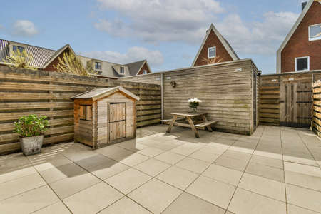 Neat paved patio with sitting area and small garden near wooden fenceの写真素材