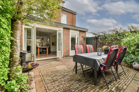 Neat paved patio with sitting area and small garden near wooden fence