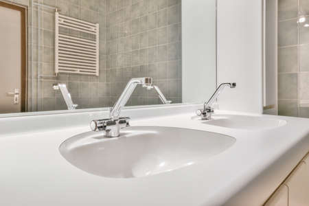 Sink with tap and liquid soap hanging on tiled wall under mirror in contemporary restroom at home
