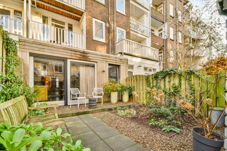 Neat paved patio with sitting area and small garden near wooden fence