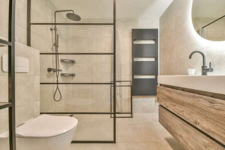 Flush toilet located between sink and shower in small tiled bathroom of contemporary apartment