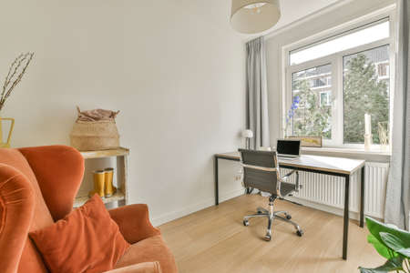 Interior of light home office with wooden desk and shelf rack near window with curtains