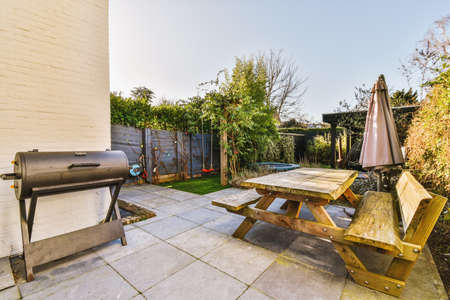Neat paved patio with sitting area and small garden near wooden fence