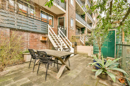 Neat paved patio with sitting area and small garden near wooden fence