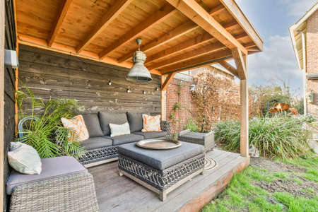 Neat paved patio with sitting area and small garden near wooden fence