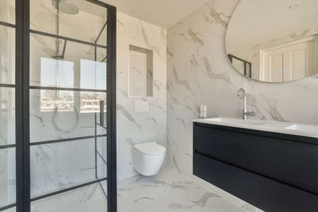 Spacious bathroom with white toilet stone sink and shower cabin in black colorin expensive apartment
