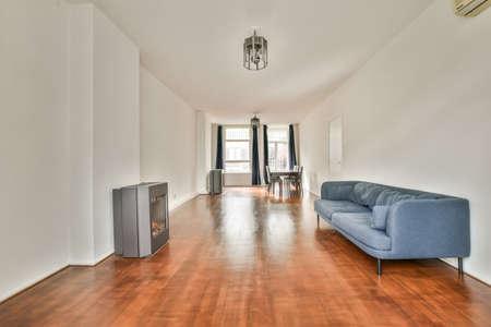 Shabby wooden table with chairs and vase located near comfortable couch against light walls with...