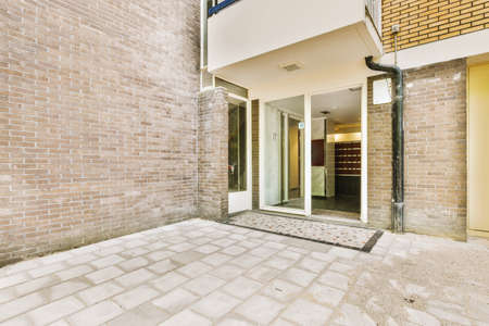 The front view of a brick building with signs,pavement and wooden doors lead to the apartmentの写真素材