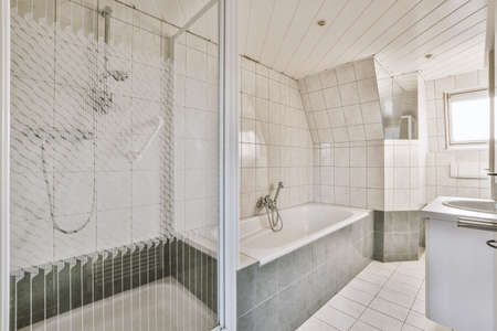 Sinks with mirrors and clean bathtub located near shower box with glass door in modern bathroom with...