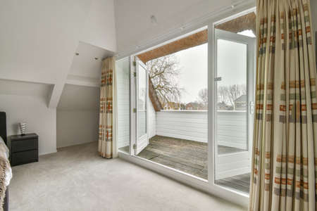 Comfortable bed placed near green wall in modern minimalist style mansard bedroom with windowsの写真素材