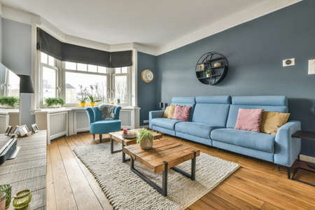 Comfortable sofa with soft cushions located under stylish chandelier in spacious light living room with archの写真素材