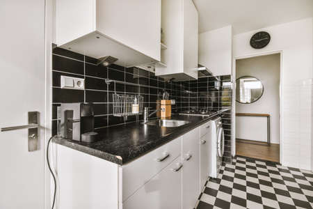 Interior of light kitchen with modern cupboards and appliances located near dining room in modern...