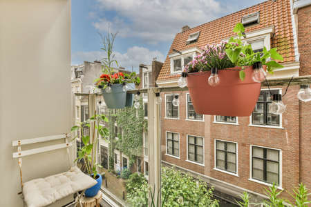 Narrow brick balcony with metal railings, wooden chair and door