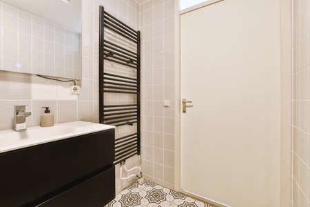 Sinks with mirrors and clean bathtub located near shower box with glass door in modern bathroom with white tiled wallsの写真素材