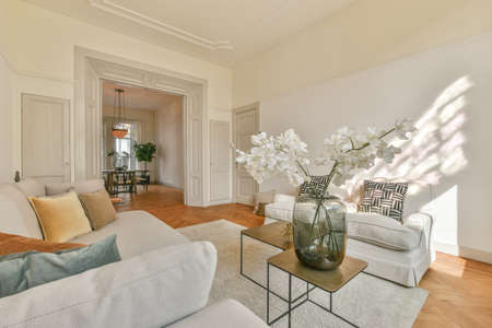 Fancy lamp hanging on ceiling over stylish furniture in spacious living room in modern flat