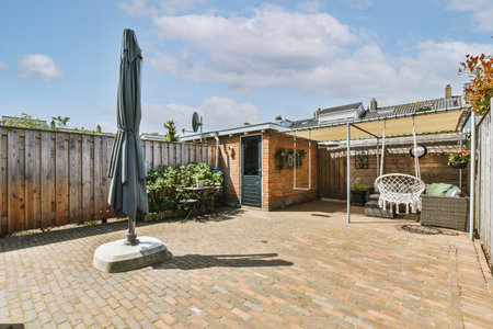 Neat paved patio with sitting area and small garden near wooden fence