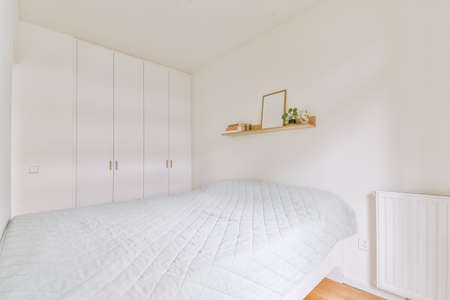 Home interior design of bedroom with bed and wooden wardrobe placed in corner near window in modern...