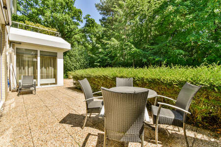 Neat paved patio with sitting area and small garden near wooden fence