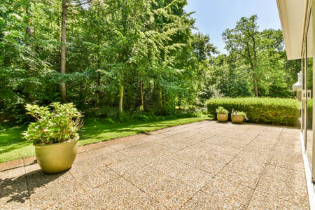 Neat paved patio with sitting area and small garden near wooden fence