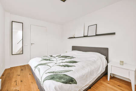 Home interior design of bedroom with bed and wooden wardrobe placed in corner near window in modern...