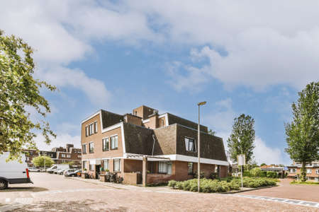 Panorama view of brick houses from an empty sidewalk street with cars, trees and lanternsの写真素材