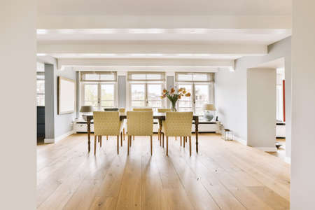 Wooden table with vase of flowers under black pendant lamp in modern living room with sofa near windowの写真素材