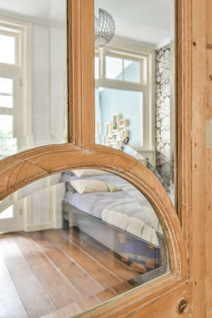 Home interior design of bedroom with bed and wooden wardrobe placed in corner near window in modern...