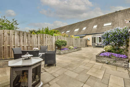 Neat paved patio with sitting area and small garden near wooden fence