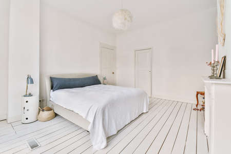 Home interior design of bedroom with bed and wooden wardrobe placed in corner near window in modern...