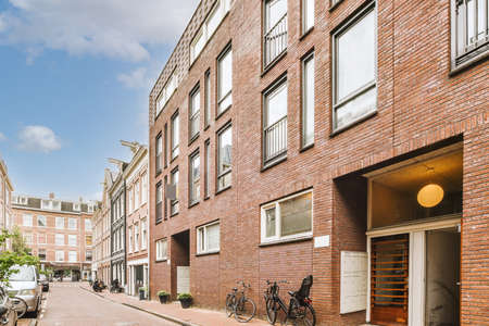 Panorama view of brick houses from an empty sidewalk street with cars, trees and lanterns