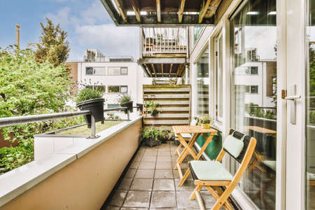 Narrow brick balcony with metal railings, wooden chair and doorの写真素材
